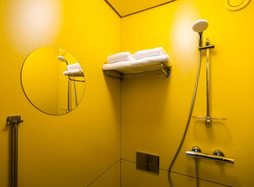 een gele badkamer met een douche en een spiegel bij SWEETS - Theophile de Bockbrug in Amsterdam