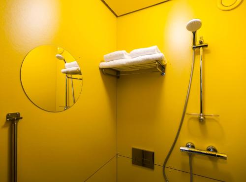 a yellow bathroom with a shower and a mirror at SWEETS - Theophile de Bockbrug in Amsterdam