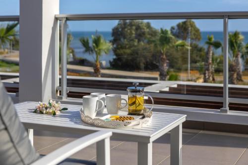 a table with a tray of food and tea on a balcony at Faros BeachFront Villa in Pervolia