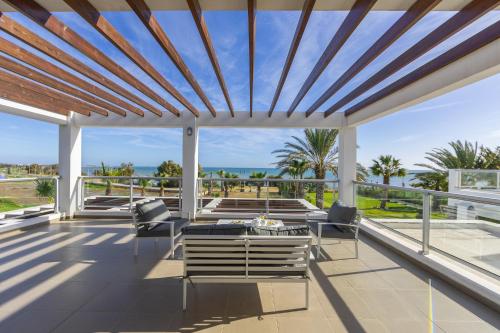 a patio with views of the ocean and palm trees at Faros BeachFront Villa in Pervolia