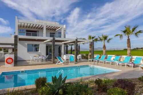 a villa with a swimming pool and palm trees at Faros BeachFront Villa in Pervolia