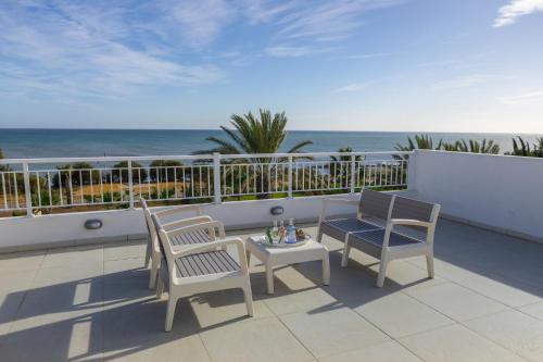 a balcony with a table and chairs and the ocean at Faros BeachFront Villa in Pervolia