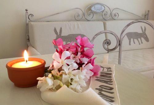 a candle and flowers on a table next to a bed at Hotel Budoni Beach in Budoni