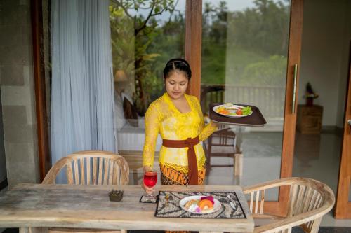 a woman in a yellow dress standing at a table at Ubud Paras Villa in Ubud