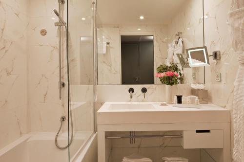 y baño blanco con lavabo y ducha. en Le 7 Eiffel Hotel by Malone, en París
