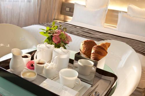 a tray with breakfast foods and coffee on a bed at Le 7 Eiffel Hotel by Malone in Paris