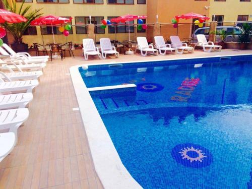 a large swimming pool with white chairs and umbrellas at Sunny Paradise Family Hotel in Kiten