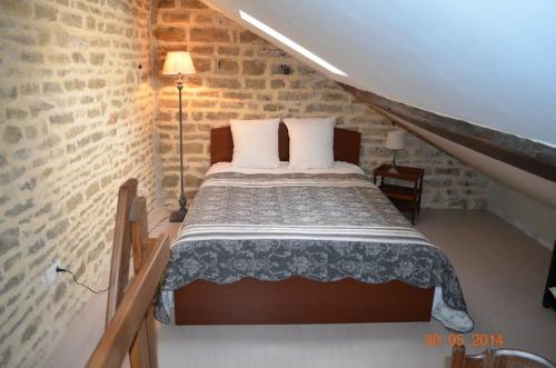 1 dormitorio con 1 cama en una pared de ladrillo en B&B Chez Marie, en Beaune