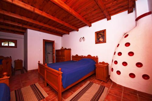 a bedroom with a blue bed and a wooden ceiling at Ócsárdi Tópanzió in Ócsárd