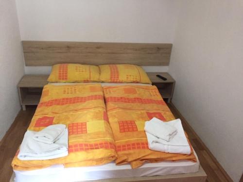 a bed with a yellow and red blanket and two pairs of shoes at Youth Hostel Nika in Kranjska Gora