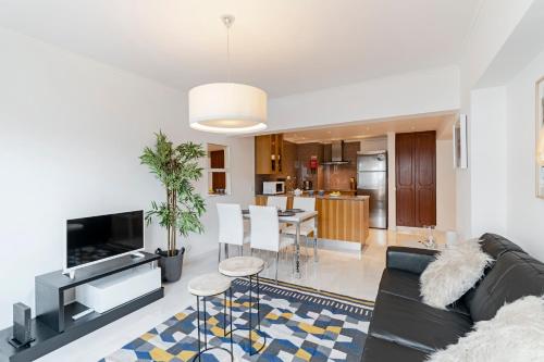 a living room with a black couch and a kitchen at Arriaga I by An Island Apart in Funchal
