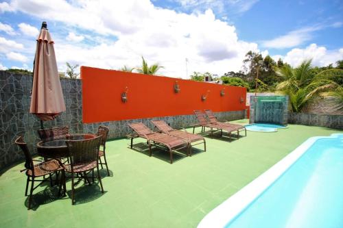 a patio with chairs and a table next to a swimming pool at Pousada Sol Nascente in Olímpia