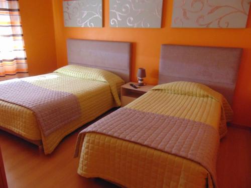 two beds in a room with orange walls at Residencial as Canárias in Ponte de Sor