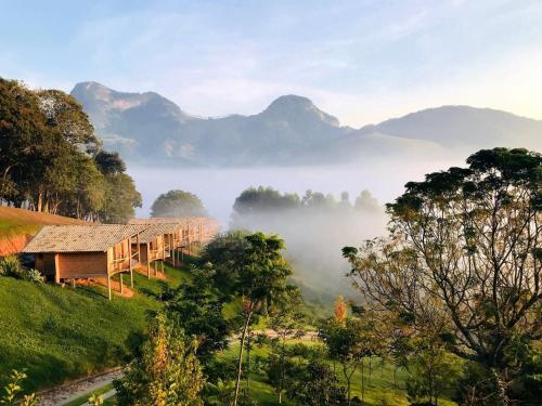 a house in the middle of a field with mountains at Pousada Caminho da Mata in São Bento do Sapucaí