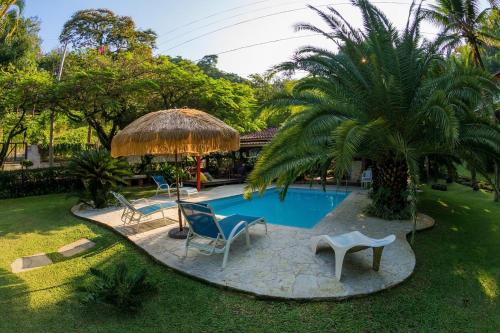 uma piscina num quintal com cadeiras e um guarda-sol em Pousada Pedras Brancas em Niterói