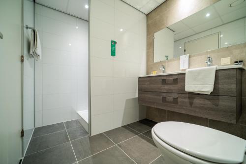 a bathroom with a toilet and a sink and a mirror at Tulip Inn Leiden Centre in Leiden