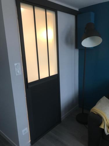 una puerta en una habitación con una lámpara y una cama en La bonbonnière de Sofi en Honfleur