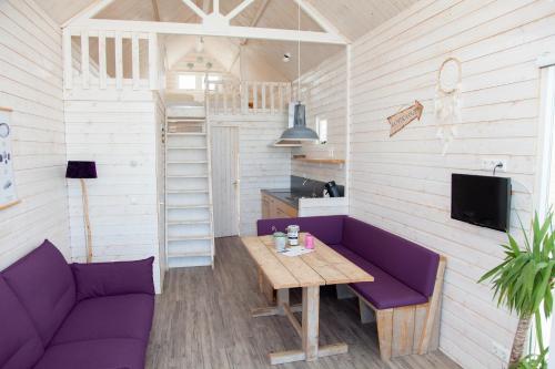 een woonkamer met een paarse bank en een tafel bij Surf en beach strandhuisjes in Katwijk