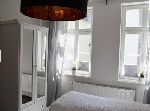 Schlafzimmer mit einem Bett und Fenstern sowie einem Kronleuchter in der Unterkunft Zum Jakobi 1 in Goslar