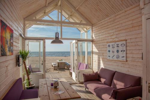een woonkamer met een bank en een tafel bij Surf en beach strandhuisjes in Katwijk