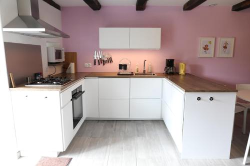 uma cozinha com armários brancos e uma parede roxa em Le Four à Pain em Leynhac
