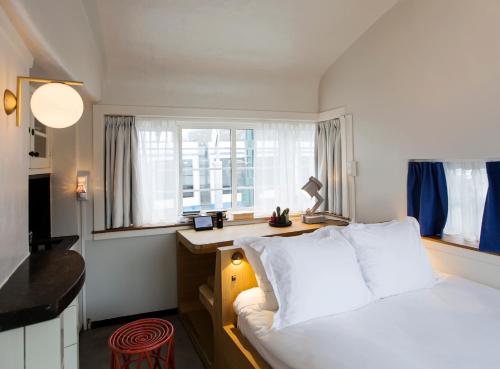 a bedroom with a bed and a desk and a window at SWEETS - Kinkerbrug in Amsterdam