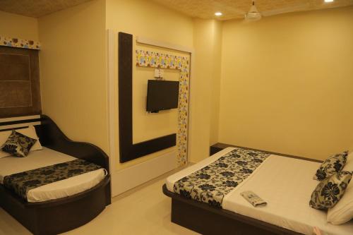 a bedroom with two beds and a tv in it at Hotel Royal Ajmer in Ajmer