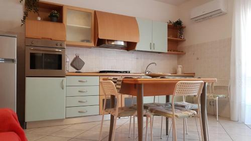 a kitchen with white cabinets and a table with chairs at La Conchiglia in Porto SantʼElpidio