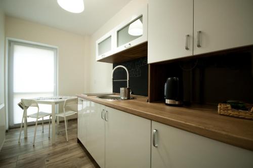 a kitchen with white cabinets and a table with a window at Dream Team Pomorska in Bydgoszcz