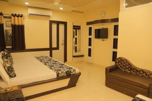 a bedroom with a bed and a couch and a television at Hotel Royal Ajmer in Ajmer