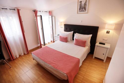 a bedroom with a bed with two pink pillows at Anjo Azul in Lisbon