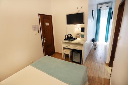 a room with a bed and a desk with a television at Anjo Azul in Lisbon