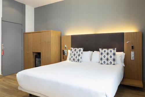 a bedroom with a large white bed with a wooden headboard at Petit Palace Plaza del Carmen in Madrid