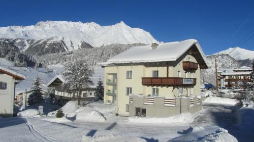 a building covered in snow with mountains in the background at Appartements Kroner in Nauders