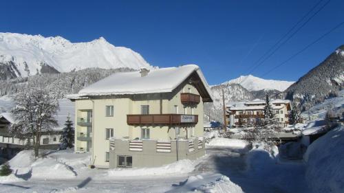 a building covered in snow with mountains in the background at Appartements Kroner in Nauders