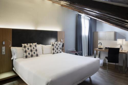a bedroom with a large white bed and a desk at Petit Palace Plaza del Carmen in Madrid