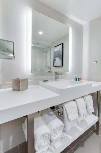 a white bathroom with a sink and towels at Radisson Hotel Seattle Airport in SeaTac