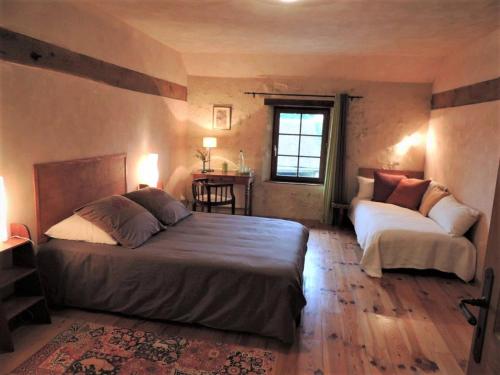 a bedroom with two beds and a table at la Maison des Aubées in Rémalard en Perche