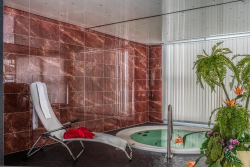 e bagno con sedia e vasca. di Wellness- und Schneesporthotel Christiania a Saas-Almagell