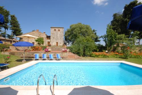 una piscina frente a una casa con un edificio en B&B La Torre - Fattoria di Larniano, en San Gimignano