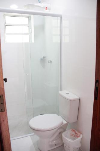a white bathroom with a toilet and a shower at Souza Reis Flat in São Thomé das Letras