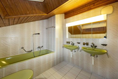 a bathroom with two green sinks and a tub at Fortuna Dachgeschoss in Grächen