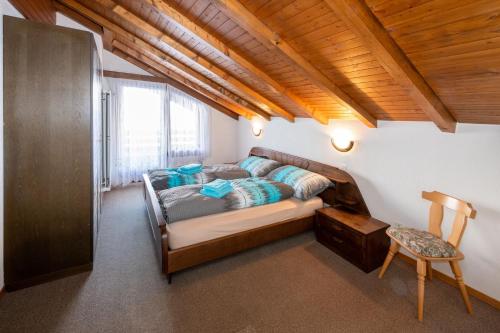 1 dormitorio con 1 cama y 1 silla en una habitación en Fortuna Dachgeschoss, en Grächen