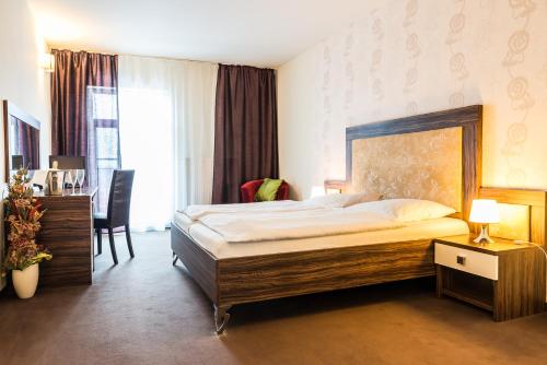 a hotel room with a large bed and a desk at Hotel Dastan in Levice