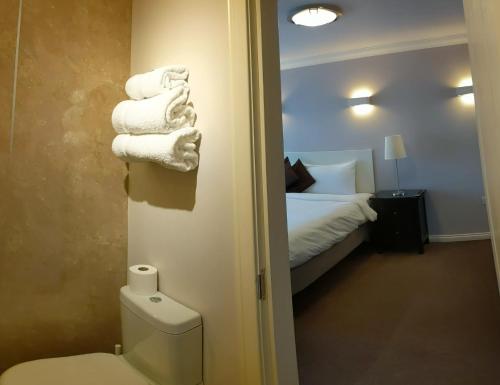 a bathroom with a toilet and a bed with towels at MacLean Guest House in Fort William