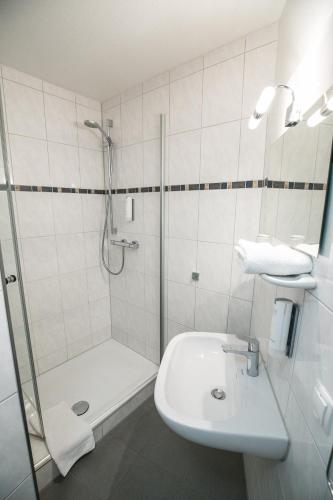 a white bathroom with a shower and a sink at Bürgermeisterkapelle in Hildesheim