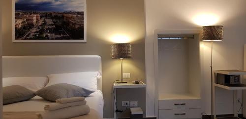 a bedroom with a white bed with two lamps at Le Stanze di Piazza Cairoli in Messina