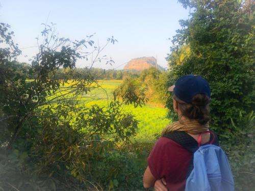 a woman with a backpack looking out at a field at Yapahuwa Relax Stay in Yapahuwa