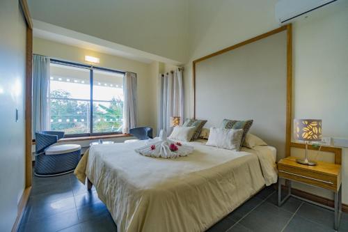 a bedroom with a large bed and a large window at Villasun Luxury Apartments & Villas in Flic-en-Flac