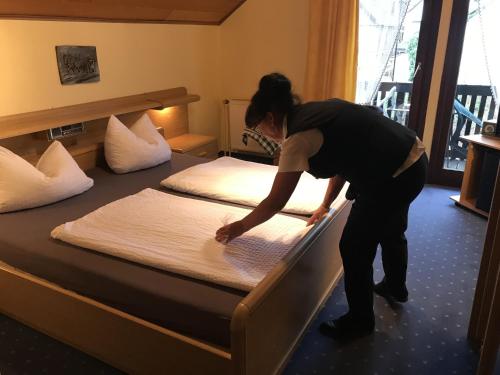 a woman making a bed in a hotel room at Hotel Hoxter Am Jakobsweg in Höxter